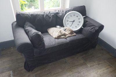 un chat allongé sur un canapé sur lequel se trouve une horloge