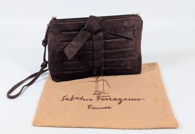the brown purse is sitting on a tan bag with a brown ribbon around it