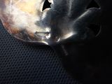 a silver spoon with a bird on it sitting on a black surface