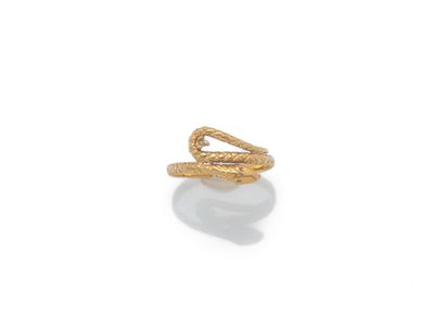 un gros plan d'une bague en forme de serpent en or posée sur une surface blanche