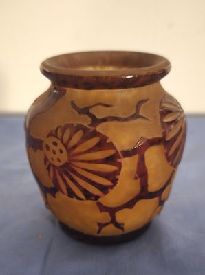 un vase marron orné d'un motif, posé sur une table bleue