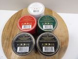 three jars of wax sitting on top of a wooden cutting board