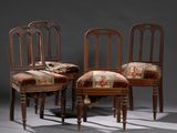 Trois chaises en bois, dotées de coussins rembourrés à motifs floraux, sont disposées devant un mur gris.