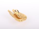 a close up of a gold bird charm on a white background