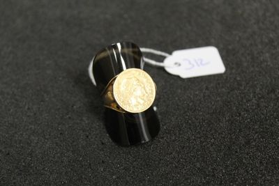 Gros plan sur une bague ornée d'une pièce d'or