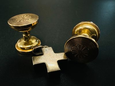 deux boutons métalliques dorés et une croix sur un fond noir