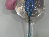 a glass spoon with a pink and blue flower inside of it