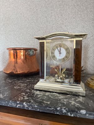 une horloge posée sur un comptoir, à côté d'une casserole en cuivre