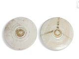 pair of white ceramic plates with holes in them on a white surface