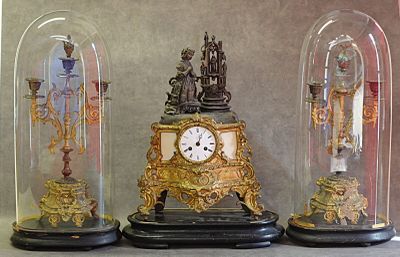 trois horloges différentes, posées sur une table sous des dômes en verre