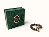 un gros plan sur un bracelet et un coffret posés sur une surface blanche