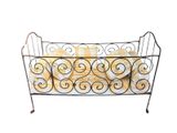 a black iron bed with a yellow and white blanket on it