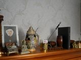 une étagère en bois sur laquelle sont posés une horloge, des vases et des photos
