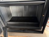 a black stove with the door open in a room