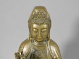 a gold statue of a buddha sitting on a white surface
