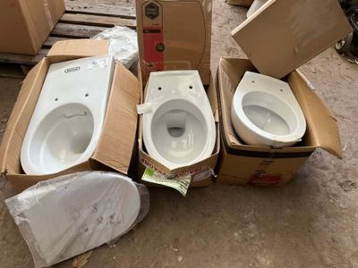 three toilets sitting in a cardboard box on the ground