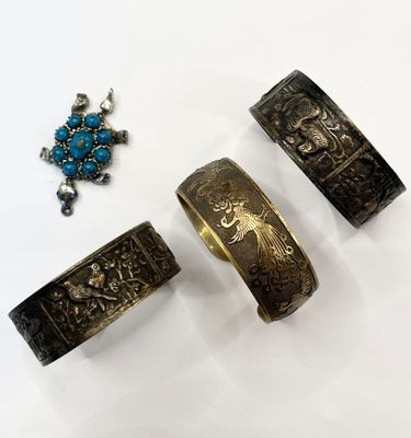 three pieces of silver and turquoise jewelry sitting on a white surface