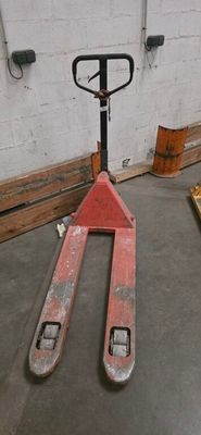 a fork lifter sitting in a warehouse with pallets in the background