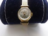 an image of a gold wrist watch on a blue velvet case