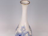 a blue and white vase with a gold rim sitting on a white surface