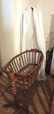 un fauteuil à bascule dans un coin d'une pièce où se trouve un rideau blanc