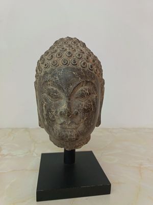 statue of a head on a black stand on a marble surface
