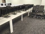 rows of computer desks in an empty room with computers on them