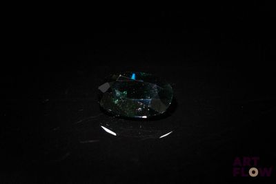 un gros plan d'un diamant vert et noir sur une surface noire