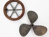 an old propeller and a wooden wheel on a white surface