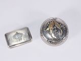 deux bijoux en argent et en or posés sur une surface blanche