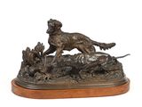 statue en bronze représentant un chien poursuivant un canard, posée sur un socle en bois