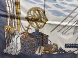 une écharpe bleue et blanche sur laquelle sont représentés un bateau et une boussole