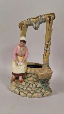 une figurine représentant une femme debout près d'un puits