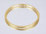 gros plan d'un bracelet en or sur une surface blanche