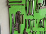 many tools hanging on a green board on the wall