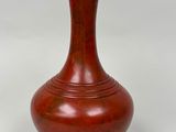 un vase rouge posé sur une surface blanche