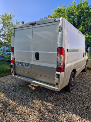 the back of a silver van parked in a gravel lot
