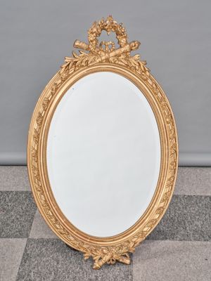 un miroir au cadre doré ouvragé posé sur un sol en damier