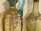 two glass vases sitting on a shelf next to each other