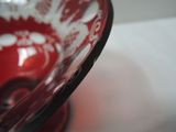 a red glass bowl with a black rim on a table