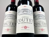 three bottles of red wine sitting on top of a white table