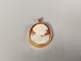 a close up of a gold plated pendant with a woman ' s face