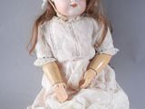a doll that is sitting on the ground with a hat on