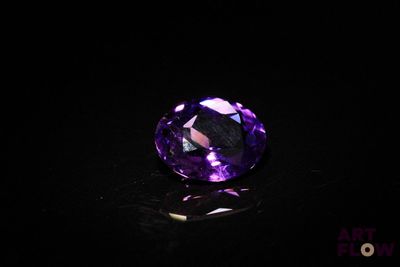 un gros plan d'une pierre précieuse violette sur une surface noire