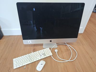 a computer monitor, keyboard and mouse on a wooden floor