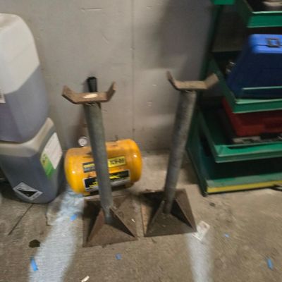 two tools that are sitting on the floor next to a trash can