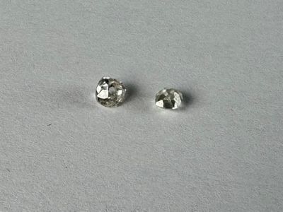 a pair of diamond stud earrings sitting on top of a white surface
