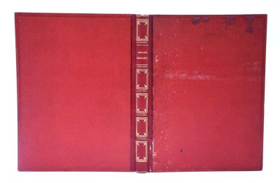 un vieux livre à la couverture rouge et à la bordure dorée
