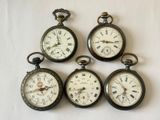 Quatre montres de poche anciennes sont exposées sur un support blanc