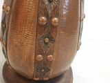 a brown vase with metal decorations on it on a stand